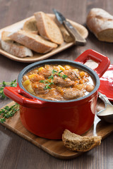 delicious vegetable stew with sausages in a pan, vertical