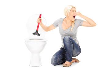Woman unclogs a stinky toilet with plunger - obrazy, fototapety, plakaty