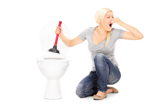 Woman unclogs a stinky toilet with plunger