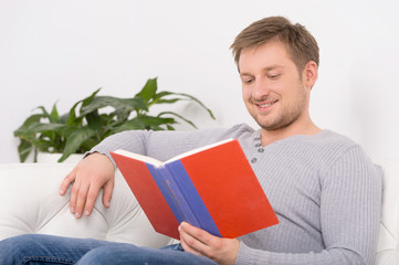 Closeup portrait of young, handsome man reading book.