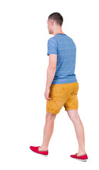 Back view of going  handsome man in shorts.  walking young guy