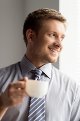 Happy businessman holding cup of coffee.