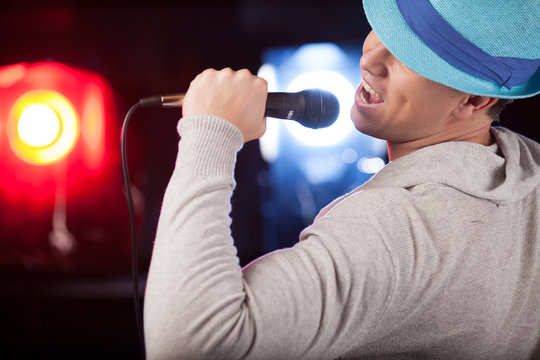 back view of male singer wearing blue hat.