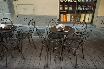 Fila di tavolini e seggiole vuoti, caffe, gelateria, bar