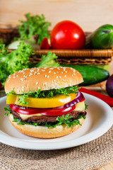 homemade hamburger with fresh vegetables on cutting board