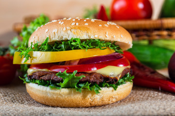homemade hamburger with fresh vegetables on cutting board