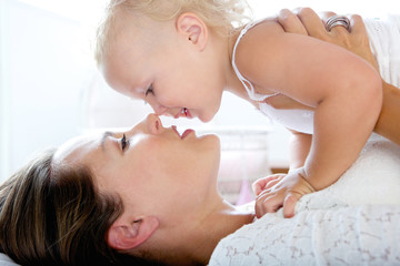 Obraz na płótnie Canvas Attractive mother kissing cute baby girl
