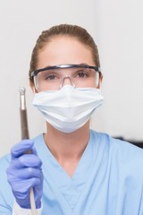 Dentist in blue scrubs holding dental drill