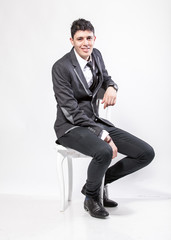 brunette man in suit sitting on chair and smiling