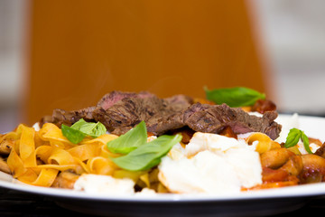 Serving of grilled beef steak and pasta