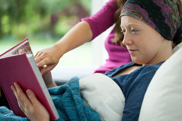 Girl with cancer holding photo album - obrazy, fototapety, plakaty