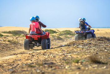 Two teams racing on quads towards the sea
