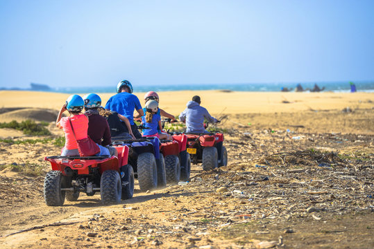 A caravan of three quads driving towards the sea