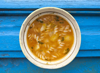 Vegetables soup with pasta on blue background