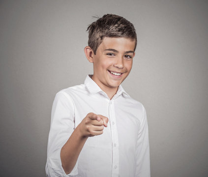 Teenager laughing, pointing finger at someone, grey background