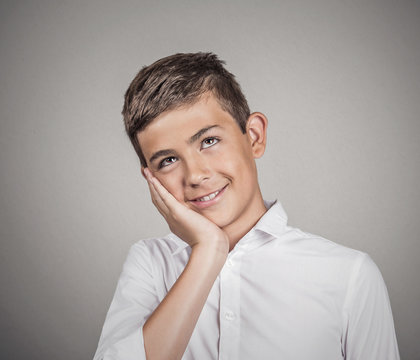  Daydreaming teenager boy in white shirt, grey wall background 