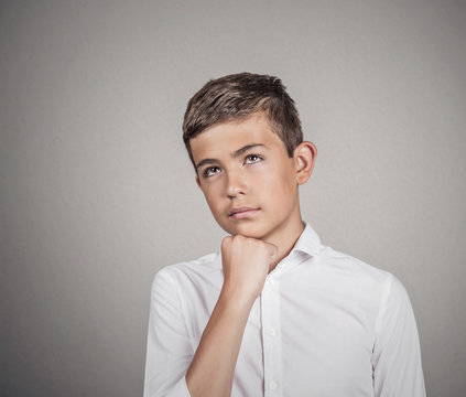  Daydreaming teenager boy in white shirt, grey wall background 