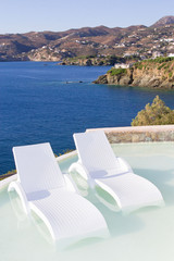 white chairs in pool with sea view