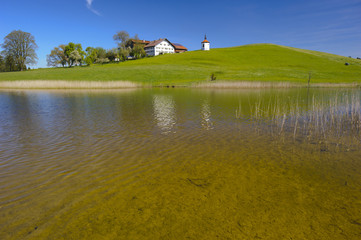 Landschaft in Bayern im Allgäu mit See und Bauernhof