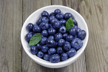 blueberries in porcelain bowl on wooden background