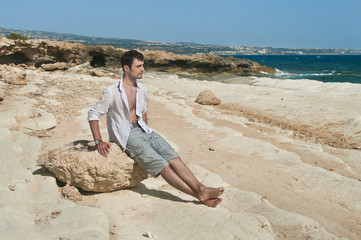 Fototapeta na wymiar man sitting on rock at sea