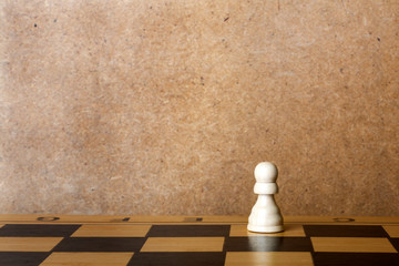 Wooden chess board with figures on green table and old wall