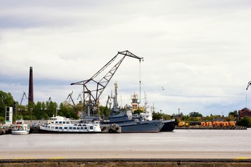 Fototapeta premium War ship and tug boat in port near crane
