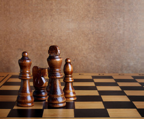 Wooden chess board with figures on table and old wall