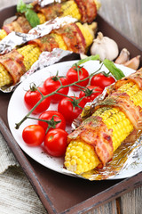 Grilled bacon wrapped corn on table, close-up