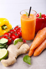 Glass of fresh carrot juice and vegetables on table cloth