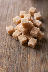 Brown sugar cubes on wooden background