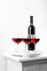 Glasses and wine bottle on tray in room