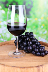 Tasty wine and ripe grape on green nature background