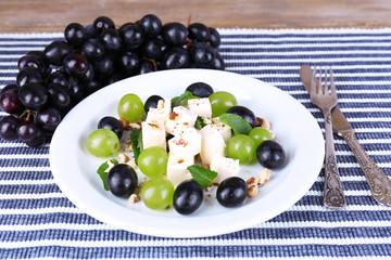tasty salad with grape and cheese on wooden table