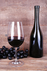 Tasty wine and ripe grape on wooden background