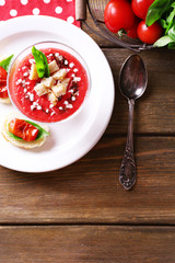 Gazpacho soup in glass bowl, on color wooden background