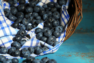 Tasty ripe blueberries in basket, on wooden table