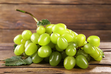 Bunch of ripe grape on wooden table on wooden wall background