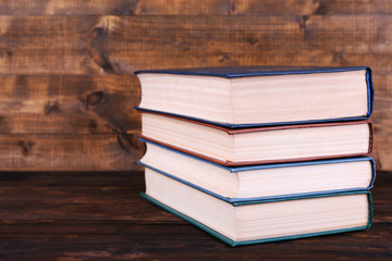 Books on wooden table on wooden wall background