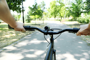 Fototapeta na wymiar Man biking fast in city park. View from bikers eyes