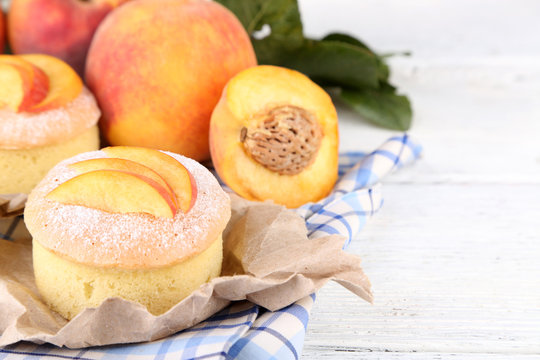 Tasty mini cakes with fresh peach, on wooden table