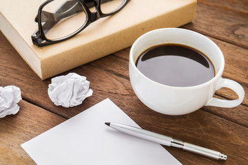 Coffee cup and book on wooden table