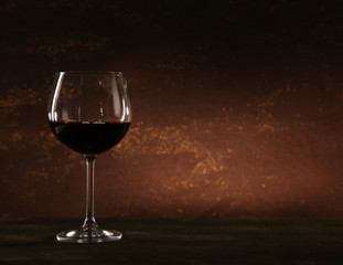 Goblet of red wine on wooden table on wooden wall background