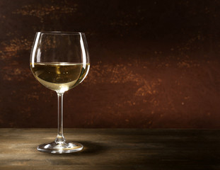 Goblet of white wine on wooden table on wooden wall background