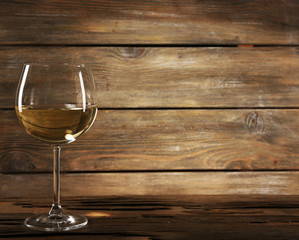 Goblet of white wine on wooden table on wooden wall background