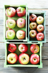 Juicy apples in boxes on wooden background
