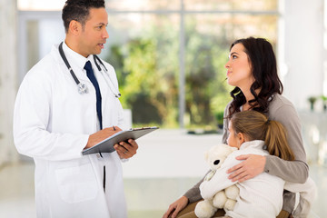 male paediatrician consulting young girl and mother