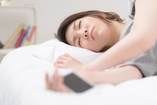 スマートフォンを持って寝落ちした女性