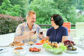 The mature couple looks at each other and clink glasses of wine