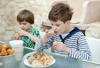 Two Brothers having healthy breakfast sitting at table on patio - 69746998